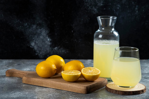 A cup of fresh lemon juice on wooden board.