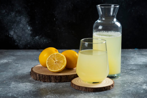 A cup of fresh lemon juice on wooden board.