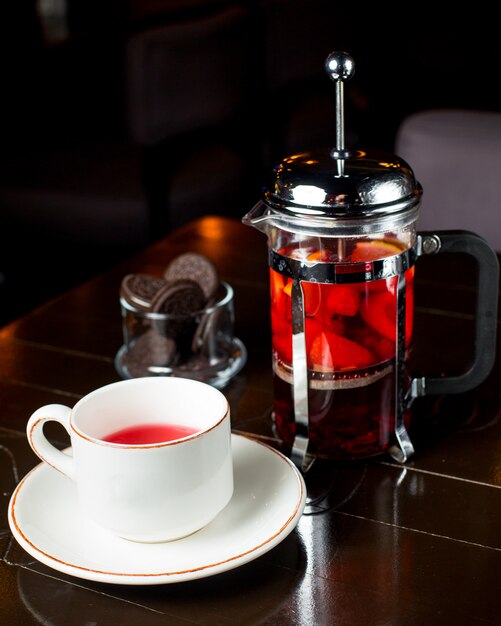 Cup of fruit tea and french press on the table