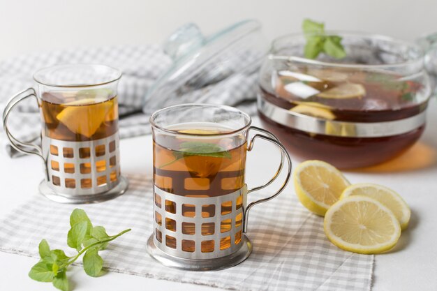 A cup of herbal tea glasses with lemon slices and mint on tablecloth