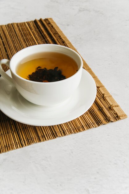 Cup of herbal tea on placemat over the concrete background