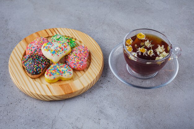 Cup of herbal tea with plate of sweet cookies on stone surface. 