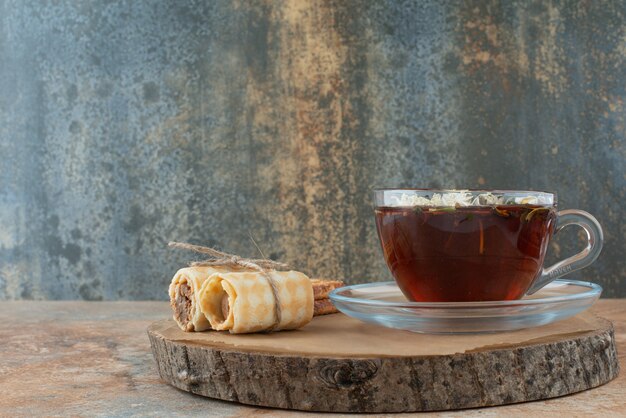 A cup of herbal tea with waffles on wooden board