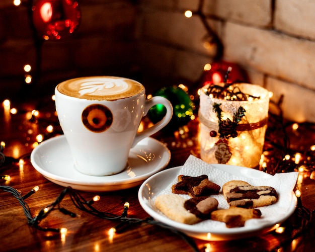 Cup of hot cappuccino and a plate with cookies