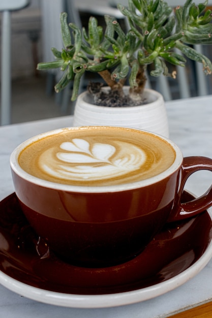 Cup of hot cappuccino with frothy foam art on the table