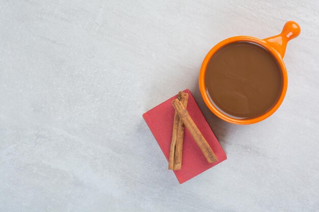Cup of hot chocolate, book and cinnamons on gray background. High quality photo