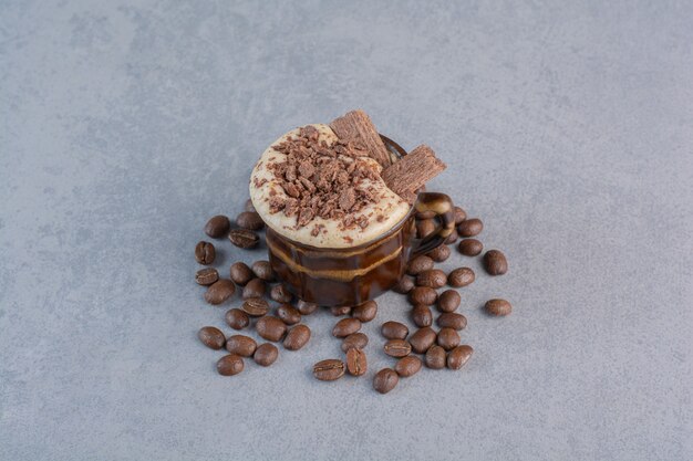 Cup of hot chocolate and coffee beans on stone background.