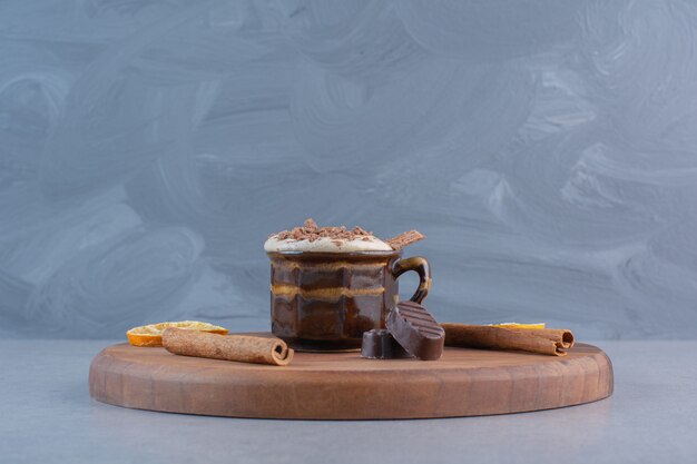 Cup of hot chocolate and tasty snacks on wooden board.