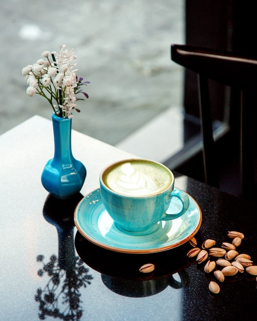 Foto gratuita tazza di caffè caldo con schiuma e pistacchi