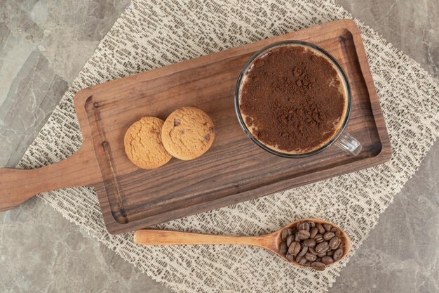 Cup of hot coffee, biscuits on wooden board with coffee beans