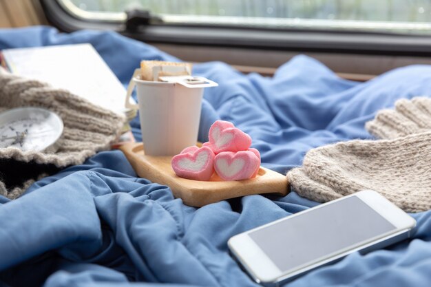 A cup of hot coffee with marshmallow near the window in the caravan 