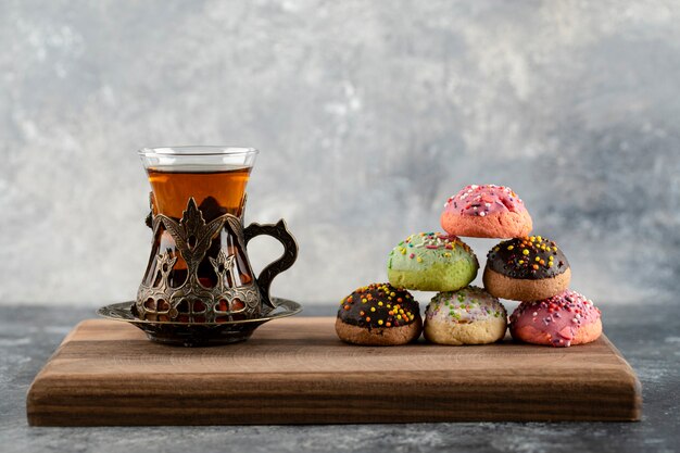 A cup of hot tea with doughnuts and sprinkles . 