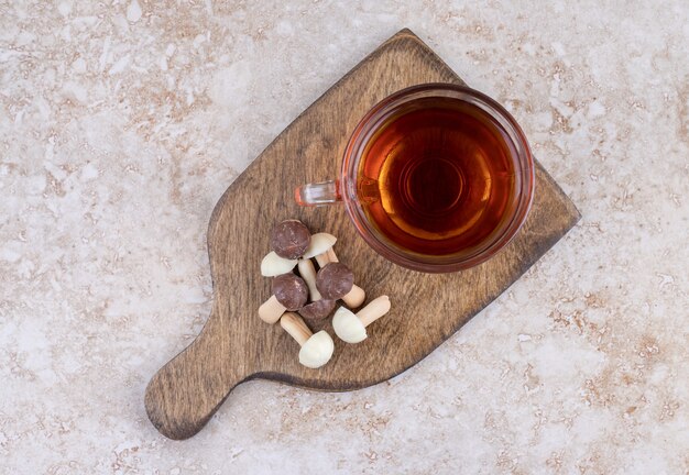 A cup of hot tea with sweet mushrooms on a wooden board