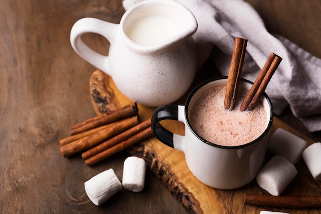 Cup of marshmallow drink with cinnamon on table