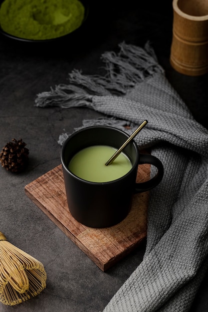 Cup of matcha tea with textile and pine cone