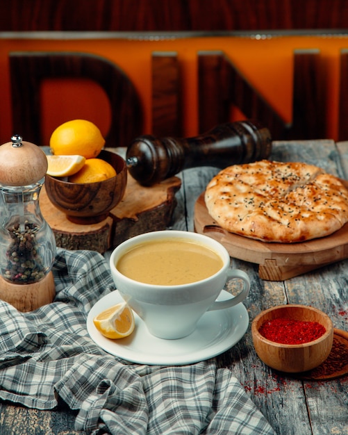 A cup of milky coffee with lemon slices and dough pie around.