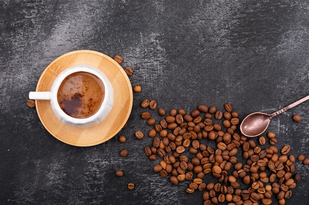 a cup of milky and foamy coffee and coffee beans top view