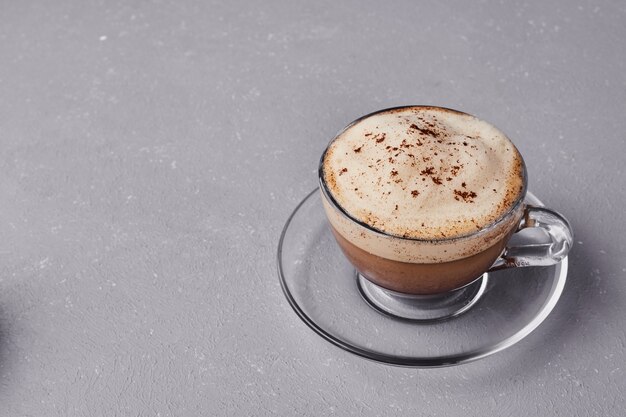 A cup of milky latte on grey background.