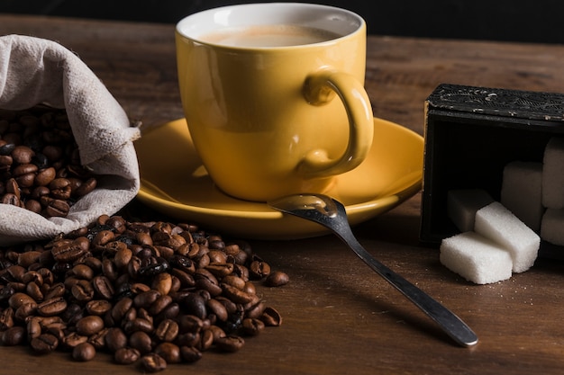 Бесплатное фото Чашка возле сахарницы и мешочек с кофейными зернами