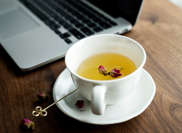 A cup of nice herbal tea next to a computer laptop
