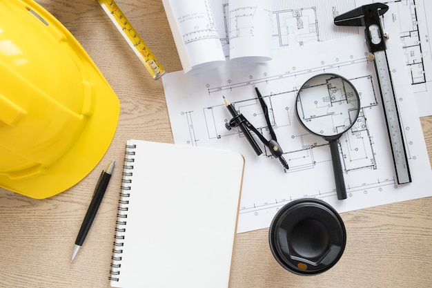 Cup and notebook near construction supplies