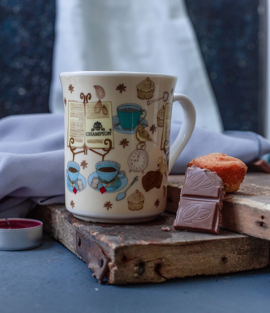 Бесплатное фото Чашка напитка, плитка шоколада и кекс на куске дерева