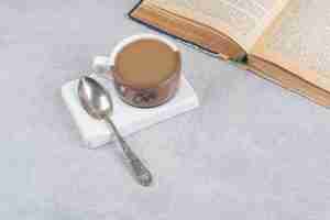 無料写真 石の表面にミルクコーヒー、スプーン、本を一杯。高品質の写真