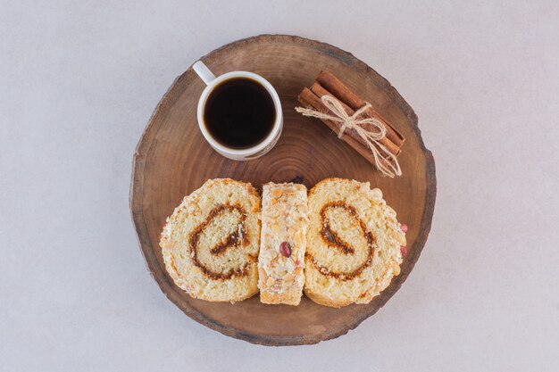 Cup off americano with cake rolls and cinnamon on wooden board 