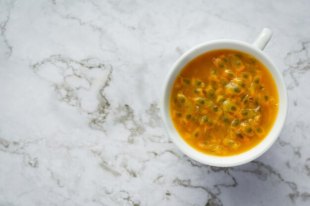 a cup of passion fruit juice place on white marble floor