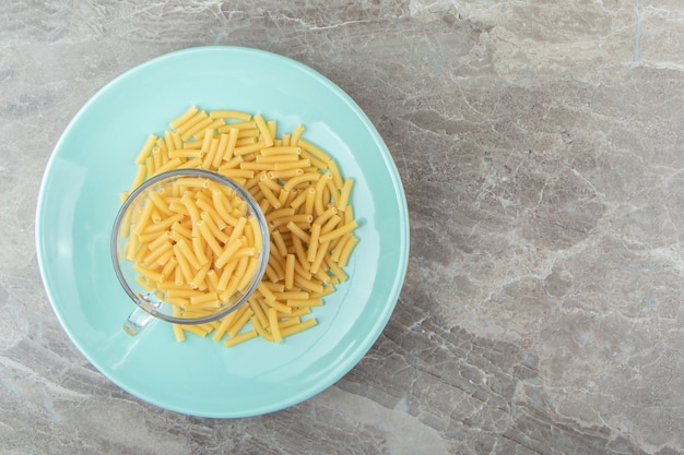 Cup of raw macaroni on blue plate