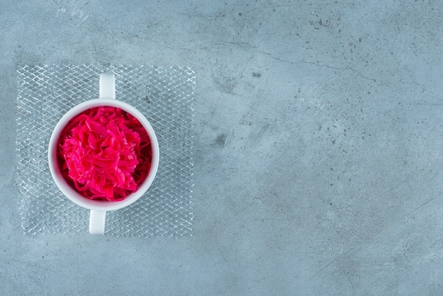 A cup of red fermented sauerkraut, on the blue table. 