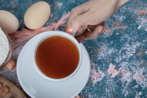 A cup of tea on a blue textured table.