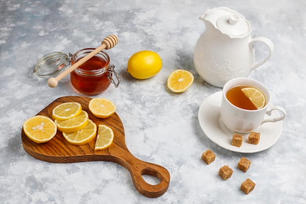 Free photo a cup of tea,brown sugar,honey and lemon on concrete  . top view, copy space