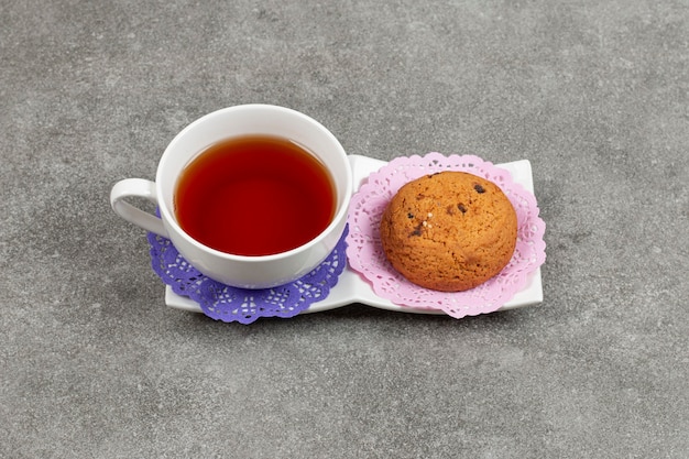 Tazza di tè e biscotti con patatine fritte sul piattino bianco