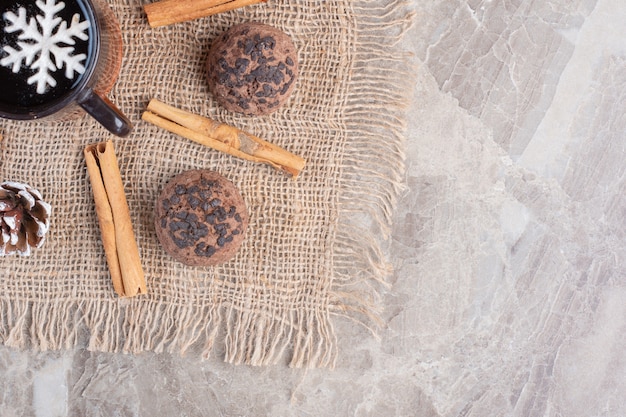 Foto gratuita tazza di tè, bastoncini di cannella e biscotti su marmo.