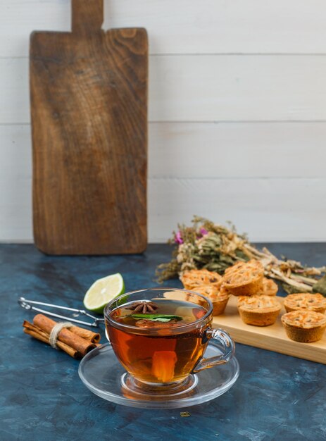 Cup of tea and cookies with cookies, flowers, cinnamon, lime and tea strainer
