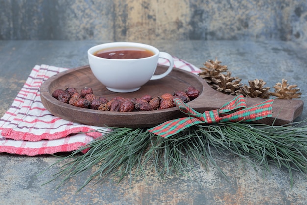 Free photo cup of tea and dried rose hip on wooden board. high quality photo