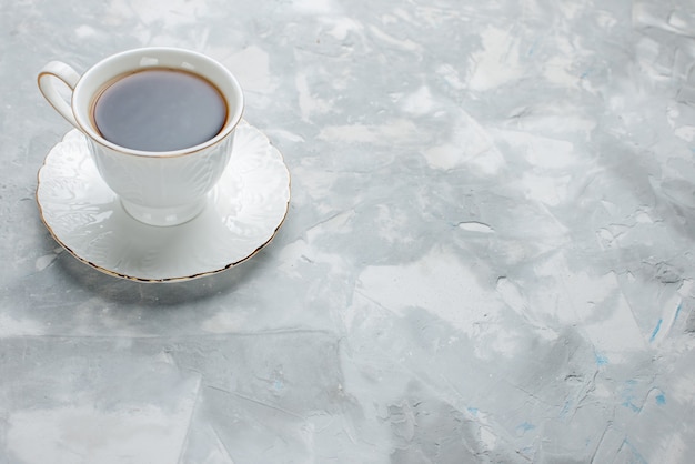 Tazza di tè caldo all'interno della tazza bianca su lastra di vetro sulla scrivania luminosa, bevanda del tè dolce