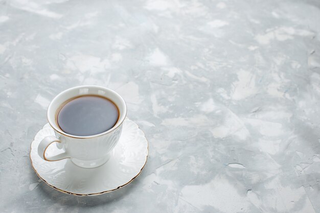 чашка горячего чая внутри белой чашки на стеклянной тарелке на белом столе, сладкий чай