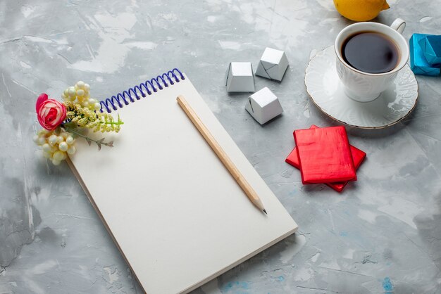 cup of tea hot inside white cup with silver anded package chocolate candies notepad on light desk, drink sweet cookie teatime