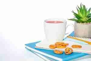 Foto gratuita una tazza di tè e quaderni su uno sfondo bianco copia spazio isolato