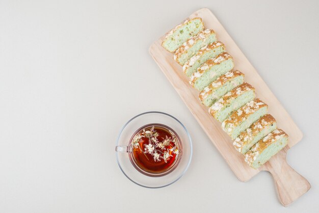 Cup of tea and pistachio cake slices on white surface