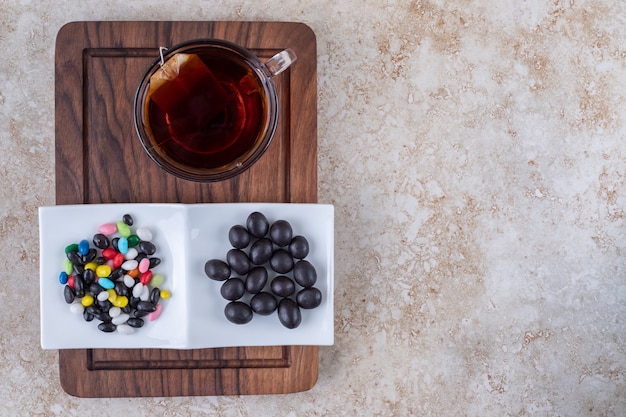 Cup of tea and plate of chocolates on wooden board