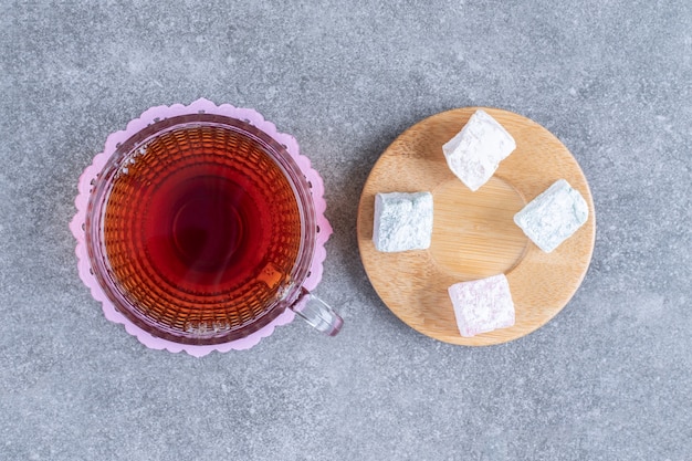 Free photo cup of tea and soft candies on marble surface