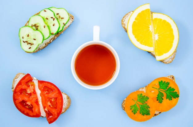 Cup of tea surrounded by assorted sandwiches