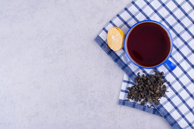 Cup of tea on tablecloth with lemon slice and dry tea. High quality photo