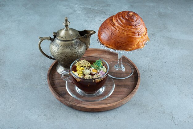 Cup of tea, teacup and pastry on wooden plate.