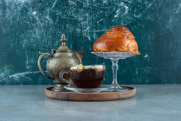 Tazza di tè, tazza da tè e pasticceria sul piatto di legno.