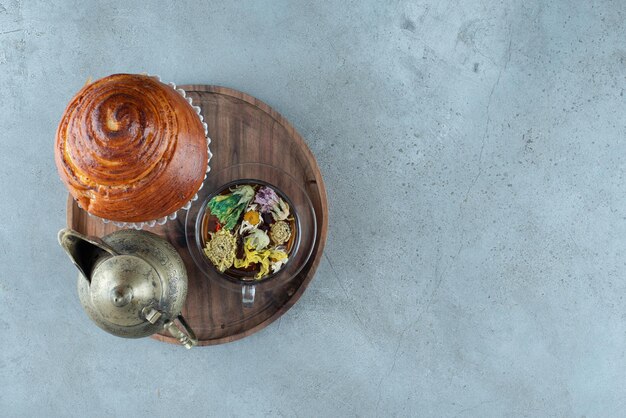 Cup of tea, teacup and pastry on wooden plate.