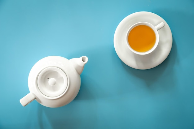 Cup of tea and teapot on a blue background flat lay
